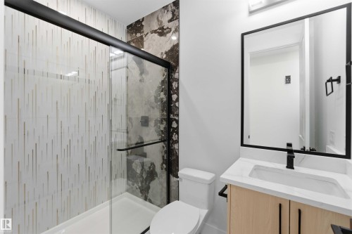 Modern bathroom featuring a glass-enclosed shower with contrasting tile patterns - 415 Pine Point(E), Leduc, AB - Indoor Photo Showing Bathroom