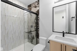 Modern bathroom featuring a glass-enclosed shower with contrasting tile patterns - 