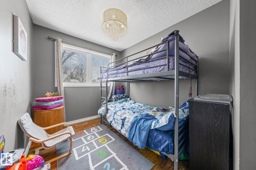 This room features hardwood flooring, a large window providing natural light, and a ceiling light fixture - 115 Warwick Road, Edmonton, AB - Indoor Photo Showing Bedroom