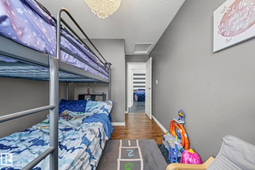 This room features a metal bunk bed, hardwood flooring, and a decorative ceiling light fixture - 115 Warwick Road, Edmonton, AB - Indoor Photo Showing Bedroom