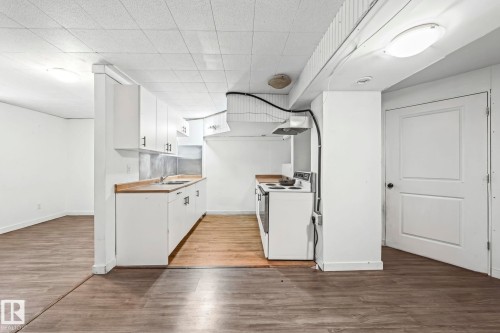 Kitchenette area featuring white cabinetry, a sink, and an electric range - 115 Warwick Road, Edmonton, AB - Indoor Photo Showing Kitchen