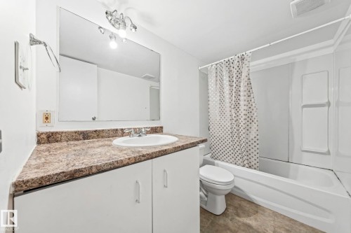 Bathroom featuring a white vanity with a patterned countertop, an integrated sink, and a large mirror - 115 Warwick Road, Edmonton, AB - Indoor Photo Showing Bathroom