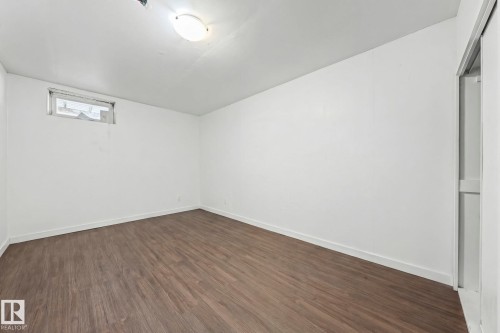 This room features wood-look flooring, white walls, and a window providing natural light - 115 Warwick Road, Edmonton, AB - Indoor Photo Showing Other Room