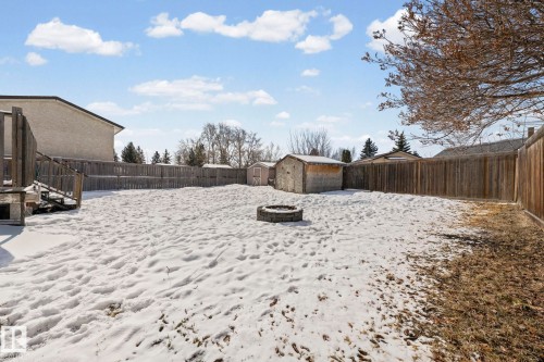 The property features a spacious yard with a wooden fence and a fire pit - 115 Warwick Road, Edmonton, AB - Outdoor