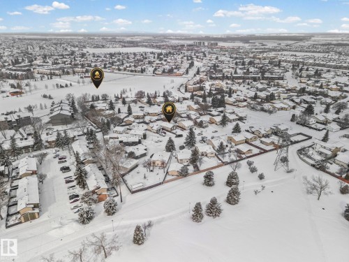 Aerial view of the surrounding neighborhood, featuring a large expanse of snow-covered land with scattered trees and residential properties - 115 Warwick Road, Edmonton, AB - Outdoor With View