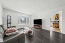 The living area features dark wood-style flooring and a large bay window, providing natural light - 115 Warwick Road, Edmonton, AB  - Indoor Photo Showing Living Room 