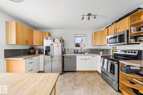 Kitchen featuring light wood upper cabinetry, stainless steel appliances, and a window above the sink - 115 Warwick Road, Edmonton, AB - Indoor Photo Showing Kitchen