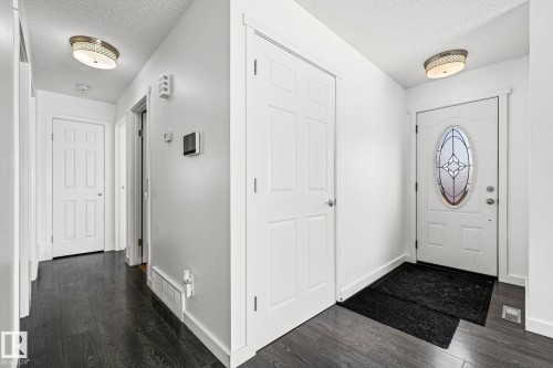 The entryway features dark wood flooring, white walls, and a white front door with decorative oval glass - 115 Warwick Road, Edmonton, AB - Indoor Photo Showing Other Room