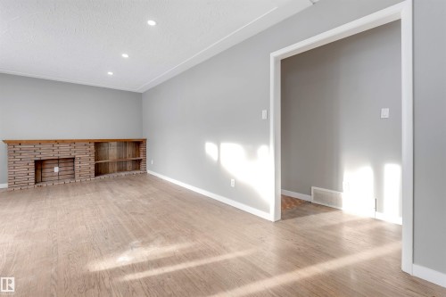 Unfurnished living room with wood finished floors, recessed lighting, and a textured ceiling - 12202 45 Street, Edmonton, AB - Indoor Photo Showing Other Room With Fireplace