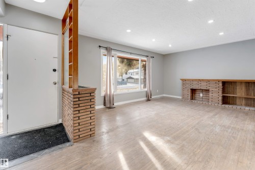 Unfurnished living room featuring a fireplace, recessed lighting, light wood-style floors, and a textured ceiling - 12202 45 Street, Edmonton, AB - Indoor With Fireplace