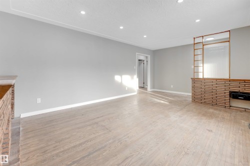Unfurnished living room with a textured ceiling, wood finished floors, and recessed lighting - 12202 45 Street, Edmonton, AB - Indoor With Fireplace
