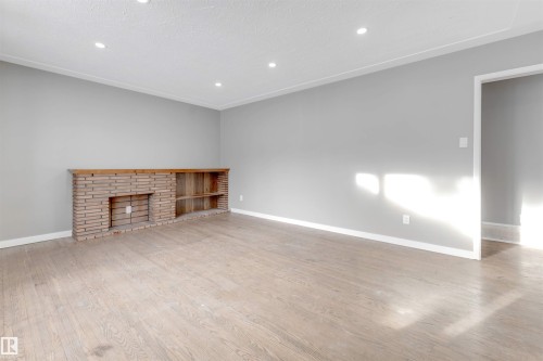 Unfurnished living room featuring recessed lighting, light wood-style floors, and a brick fireplace - 12202 45 Street, Edmonton, AB - Indoor With Fireplace