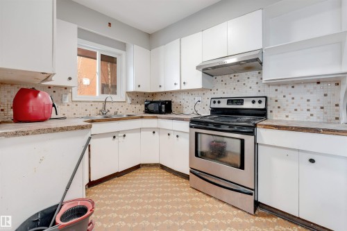 Kitchen featuring light floors, stainless steel electric stove, white cabinetry, under cabinet range hood, and open shelves - 12202 45 Street, Edmonton, AB - Indoor Photo Showing Kitchen With Double Sink