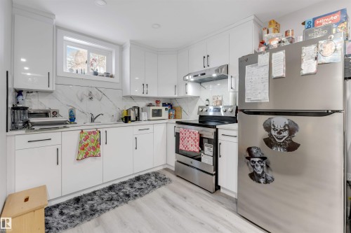 Kitchen featuring stainless steel appliances, white cabinetry, light countertops, and under cabinet range hood - 12202 45 Street, Edmonton, AB - Indoor Photo Showing Kitchen