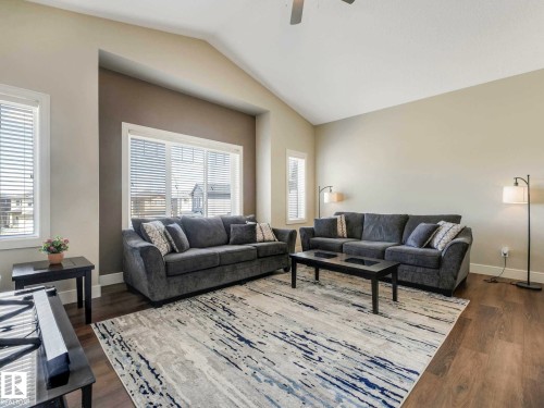 Spacious living area featuring vaulted ceilings, multiple large windows with blinds, wood-finish flooring, and neutral wall tones - 16251 135 Street Nw, Edmonton, AB - Indoor Photo Showing Living Room