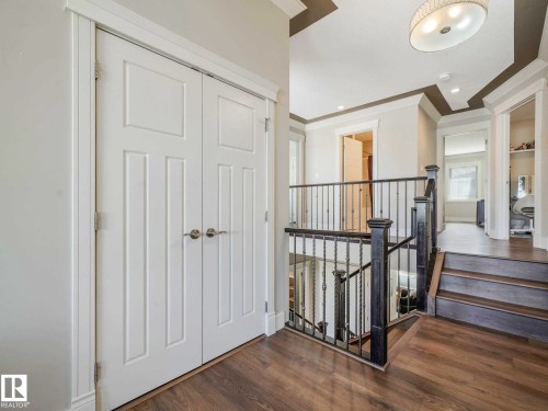Entryway featuring white bi-fold doors with panel detailing, dark wood-finish flooring, and a decorative ceiling light fixture - 16251 135 Street Nw, Edmonton, AB - Indoor Photo Showing Other Room