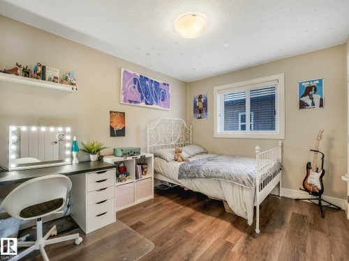 Bedroom featuring wood-finish flooring, a double-pane window, and a built-in floating shelf - 16251 135 Street Nw, Edmonton, AB - Indoor Photo Showing Bedroom