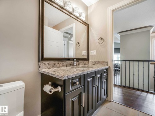 Bathroom vanity with granite-style countertop, undermount sink, and dark wood-finish cabinetry - 16251 135 Street Nw, Edmonton, AB - Indoor Photo Showing Bathroom