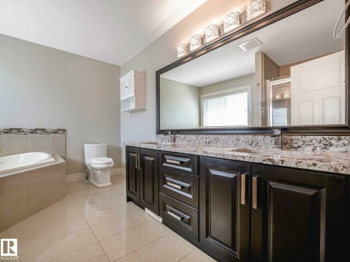 Double vanity with dark wood cabinetry and stone countertops - 16251 135 Street Nw, Edmonton, AB - Indoor Photo Showing Bathroom