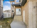 Stucco exterior featuring a double-door entry with arched glass inserts, concrete steps with a black metal handrail, and white framed windows - 16251 135 Street Nw, Edmonton, AB  - Outdoor 