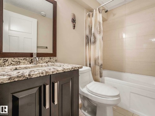 Bathroom featuring a vanity with a light-toned patterned countertop, a built-in sink with a chrome faucet, and a framed mirror - 16251 135 Street Nw, Edmonton, AB - Indoor Photo Showing Bathroom