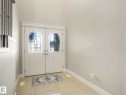 Double entry doors with decorative arched glass inserts, white trim, and light-toned tile flooring - 16251 135 Street Nw, Edmonton, AB  - Indoor Photo Showing Other Room 