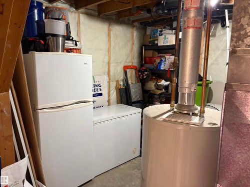 Utility room featuring a water heater, exposed ceiling joists, and concrete flooring - 410 Main St, Alcomdale, AB - Indoor Photo Showing Laundry Room