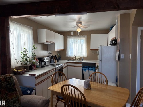 U-shaped kitchen layout featuring light wood-finish cabinetry, white countertops, and a ceiling fan with integrated lighting - 410 Main St, Alcomdale, AB - Indoor