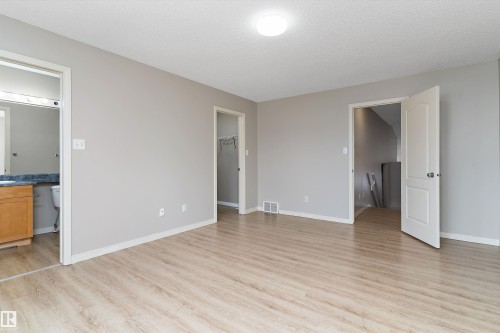 Spacious room featuring wood-finish flooring, light gray wall paint, and white trim - 15109 Miller Boulevard, Edmonton, AB - Indoor Photo Showing Other Room