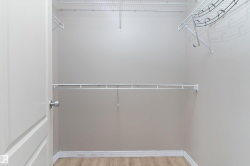 Walk-in closet featuring wire shelving, wire hanging rods, and wood-finish flooring - 15109 Miller Boulevard, Edmonton, AB - Indoor With Storage