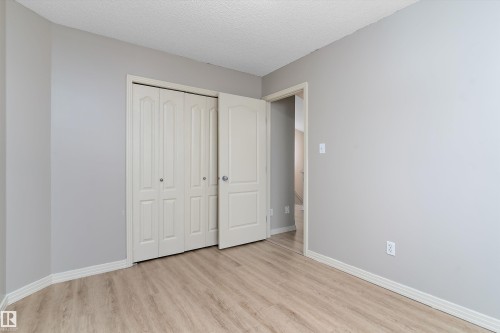 Neutral-toned room featuring wood-finish flooring and light gray walls - 15109 Miller Boulevard, Edmonton, AB - Indoor