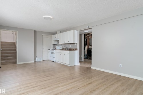 Open-concept living space featuring wood-finish flooring and a compact kitchen - 15109 Miller Boulevard, Edmonton, AB - Indoor Photo Showing Kitchen