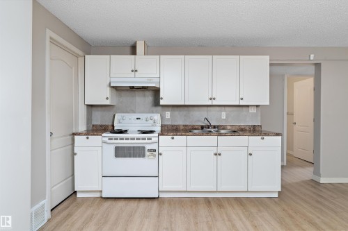 Kitchen featuring white cabinetry, a white electric range, a double basin sink, and wood-finish flooring - 15109 Miller Boulevard, Edmonton, AB - Indoor Photo Showing Kitchen With Double Sink