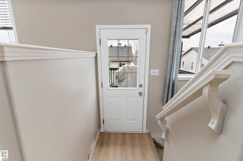 Entry area featuring a white door with glass inserts, wood-finish flooring, light neutral paint, and white trim - 15109 Miller Boulevard, Edmonton, AB - Indoor Photo Showing Other Room