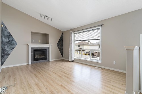 Spacious interior featuring wood-finish flooring and a vaulted ceiling - 15109 Miller Boulevard, Edmonton, AB - Indoor Photo Showing Living Room With Fireplace