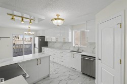 Bright kitchen featuring white cabinetry, gold-tone hardware, and marble-look countertops and flooring - 