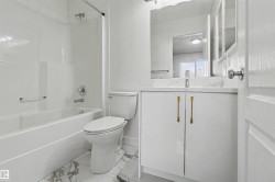Bathroom featuring a white vanity with gold-tone hardware, a rectangular sink, and a large mirror - 