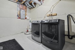 Dedicated laundry area with a painted concrete floor, exposed ceiling joists, and visible electrical panel - 