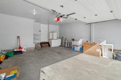 Spacious garage featuring a concrete floor, light gray walls, white panel garage door, and recessed lighting - 