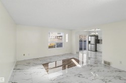 Spacious room featuring large format marble-look tile flooring, white painted walls, and abundant natural light from a double-pane window - 