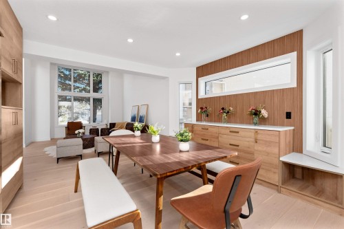 Open-concept living space featuring wood-finish flooring, recessed lighting, and a prominent built-in wood-paneled wall unit with integrated cabinetry and a horizontal window - 607 Butterworth Wynd, Edmonton, AB - Indoor Photo Showing Dining Room