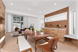 Open-concept living space featuring wood-finish flooring, recessed lighting, and a prominent built-in wood-paneled wall unit with integrated cabinetry and a horizontal window - 