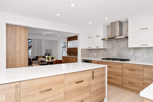 Contemporary kitchen featuring wood-finish lower cabinetry with white upper cabinets and brushed metal hardware - 607 Butterworth Wynd, Edmonton, AB - Indoor Photo Showing Kitchen