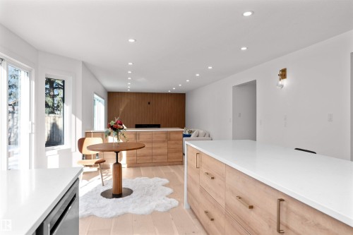 Modern kitchen featuring light wood-finish flooring, white countertops, built-in cabinetry with gold-tone hardware, recessed ceiling lighting, and a sliding glass door - 607 Butterworth Wynd, Edmonton, AB - Indoor Photo Showing Other Room