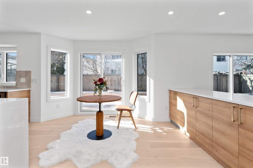 Bright kitchen and dining area featuring light wood-finish flooring, white walls, recessed lighting, and expansive windows - 607 Butterworth Wynd, Edmonton, AB - Indoor