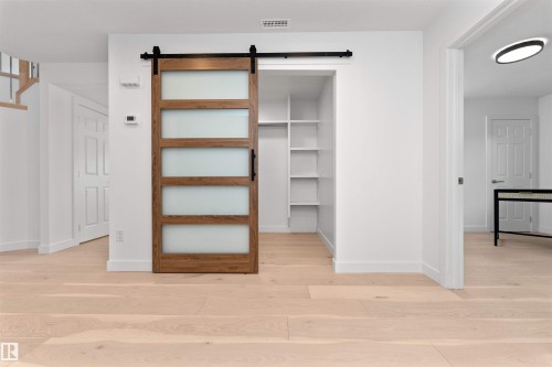 Modern barn door with frosted glass panels and a black hardware track - 607 Butterworth Wynd, Edmonton, AB - Indoor Photo Showing Other Room