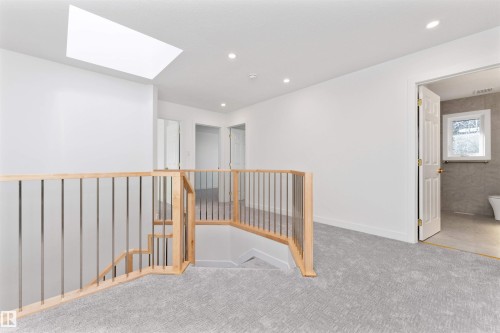 Upper-level hallway featuring light gray patterned carpeting and a wood-finish staircase with metal balusters - 607 Butterworth Wynd, Edmonton, AB - Indoor Photo Showing Other Room