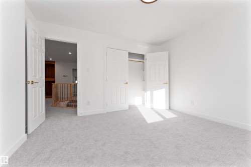 Bedroom featuring light-toned carpeting, white walls, and bright overhead lighting - 607 Butterworth Wynd, Edmonton, AB - Indoor Photo Showing Other Room