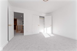 Bedroom featuring light-toned carpeting, white walls, and bright overhead lighting - 