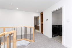 Open landing featuring light wood-finish railing with metal spindles, recessed lighting, and soft grey carpet flooring - 